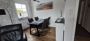 Essecke frisch renoviert und neuer echt Holzboden Februar 2026 mit großem Tisch und 4 gemütlichen Stühlen - Bild 10: Nordsee Ferienhaus Dornumersiel strandnah - Hund willkommen - WLAN