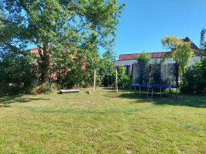Der grosse Garten lädt zum Spielen ein. Hier gibt es eine grosse Freifläche sowie eine eingerichtete Spielecke für die Kinder. Dort befinden sich Schaukeln, ein Sandkasten, ein Trampolin sowie eine Gartenhütte mit Spielsachen und Fahrzeugen für die Kinder. - Bild 1: Nordseenahes Ferienhaus in Ostfriesland für Familie und Co