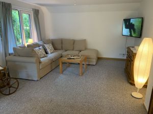 Im Wohn- und Esszimmer findest Du eine gemütliche Couch, die zu einem Bett (140 x 200) ganz einfach umgebaut werden kann. Der große SMART TV an der Wand ist drehbar. - Bild 5: Ferienhaus Muschel an der Nordsee
