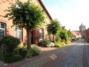 vorbei an kleinen Landarbeiterhäusern Richtung Kirche erreichen Sie in 2 Gehminuten den Dorfladen und das Restaurant Alte Brauerei - Bild 11: Apartment Eulennest in ostfriesischem Gulfhof in Pilsum Nähe Greetsiel