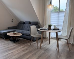 Das gemütliche Sofa lädt um Kuscheln ein, der Tisch ist ideal zum Kartenspielen oder Essen. Ein Küchentisch ist zusätlich vorhanden. Rechts die Türen zum Balkon, wo der Blick richtung Osten Morgensonne verspricht. - Bild 1: Haus Likedeeler Wangerooge